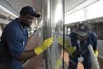 Metro employees clean a glass panel on a Metrorail station platform.