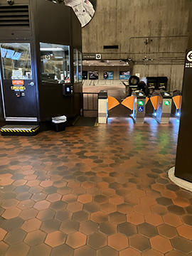 A picture of the faregates at the D St and 7th St exit. The ADA faregate is closest to the station manager's kiosk.
